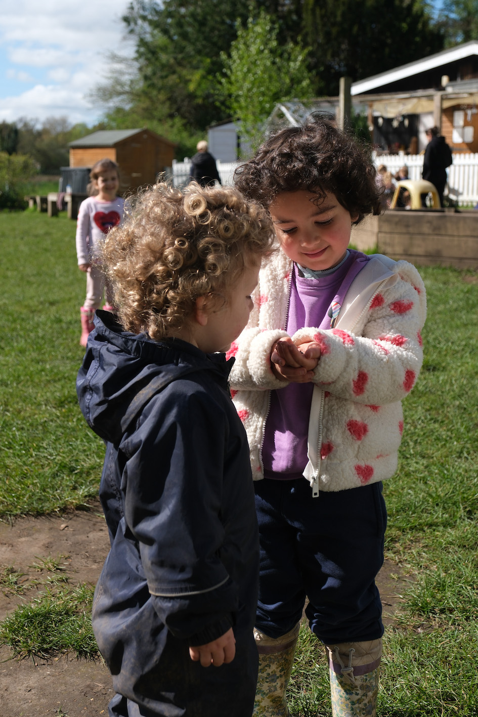 Children playing with yellow trucks in the garden.